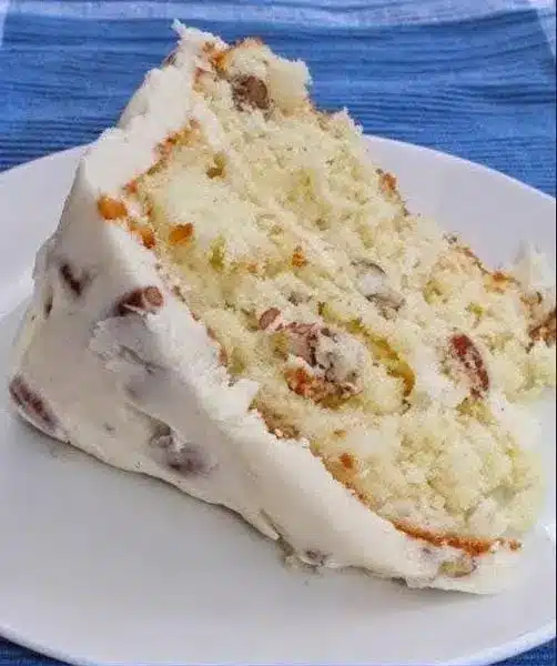 A slice of Italian cream cake on a plate showing the moist crumb and coconut texture
