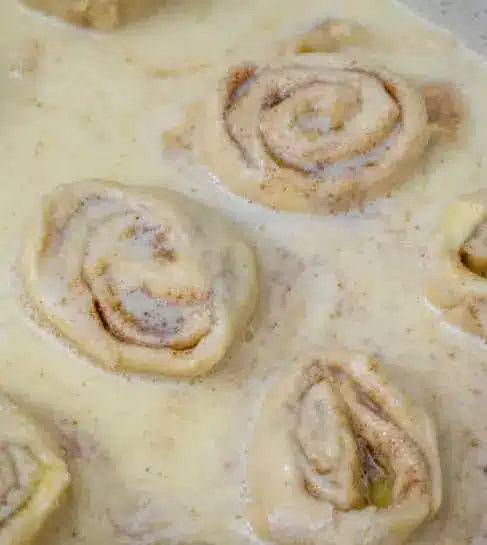 Individual southern butter roll served in a bowl with extra custard sauce drizzled over the top.