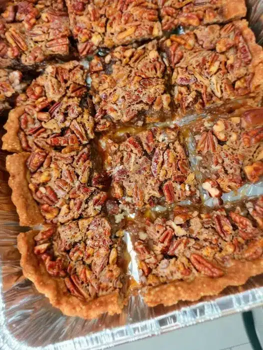A slice of southern pecan pie with a thick custard layer and crunchy nut topping.