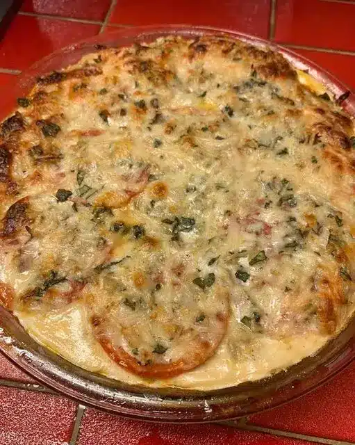 A sliced southern tomato pie showing layers of basil and melted cheddar