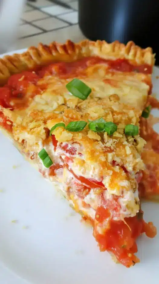 A sliced portion of tomato pie showing the layers of tomatoes and herbs.