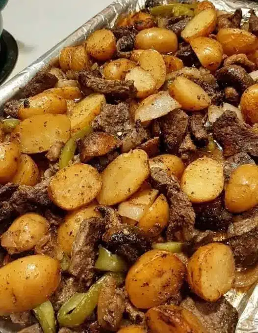 A sliced ribeye steak with golden brown potatoes and a sprig of rosemary.