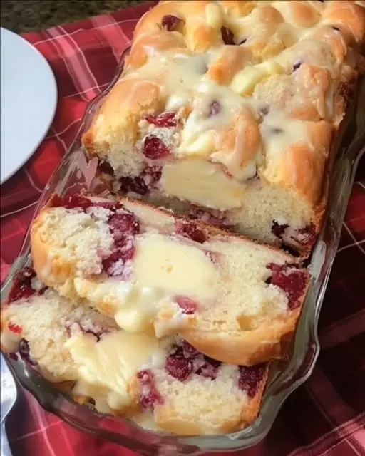 Sliced cranberry cream cheese bread on a white plate with a sprig of mint