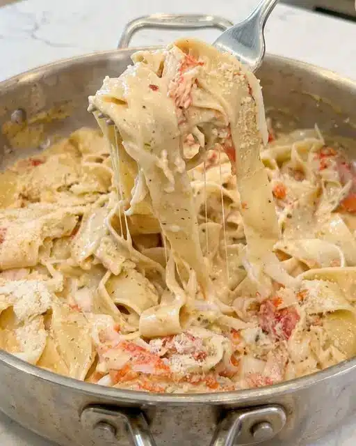 Plated creamy crab pappardelle pasta garnished with parsley and lemon wedges