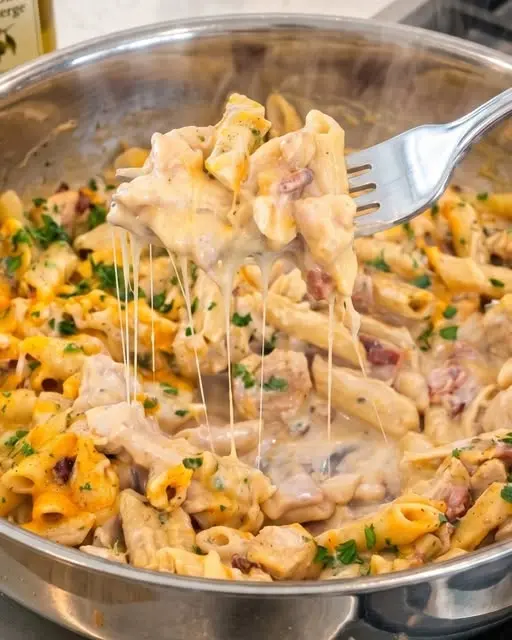The finished creamy crack chicken penne served in a bowl with green onion garnish.