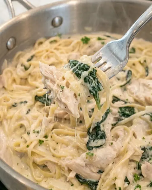 The finished creamy four cheese chicken pasta served in a bowl with a side of garlic bread.
