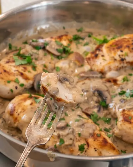 The finished creamy garlic mushroom chicken served in a skillet with a side of steamed vegetables