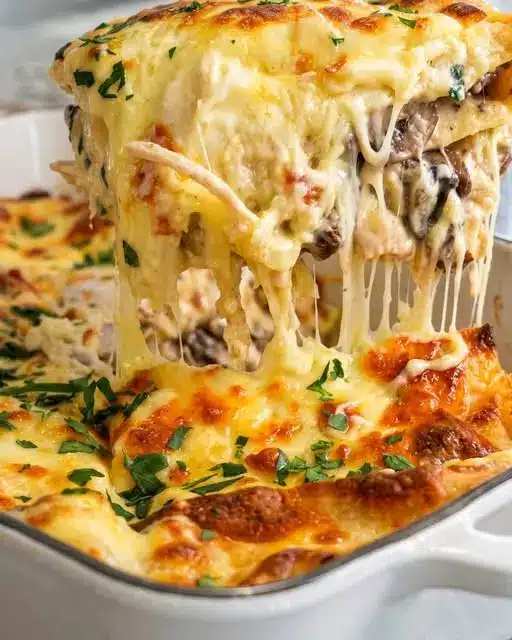 A perfectly sliced square of white chicken lasagna on a white plate, showing the creamy layers and spinach.
