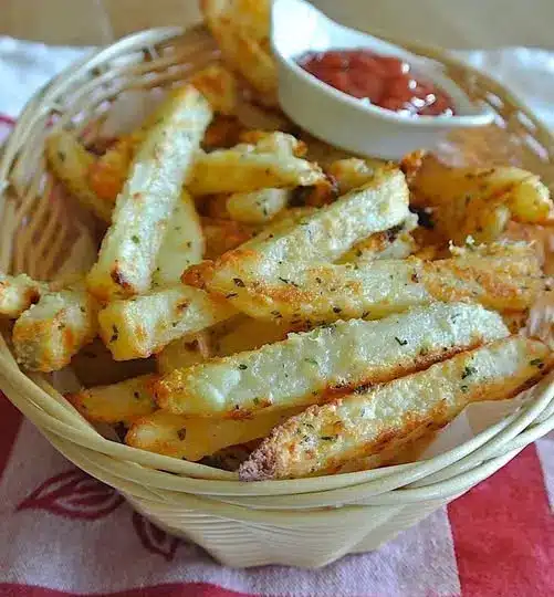 A bowl of golden brown potato wedges served with a side of creamy dipping sauce