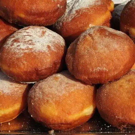 A bite taken out of a pÄ…czki showing the rich vanilla custard filling inside.