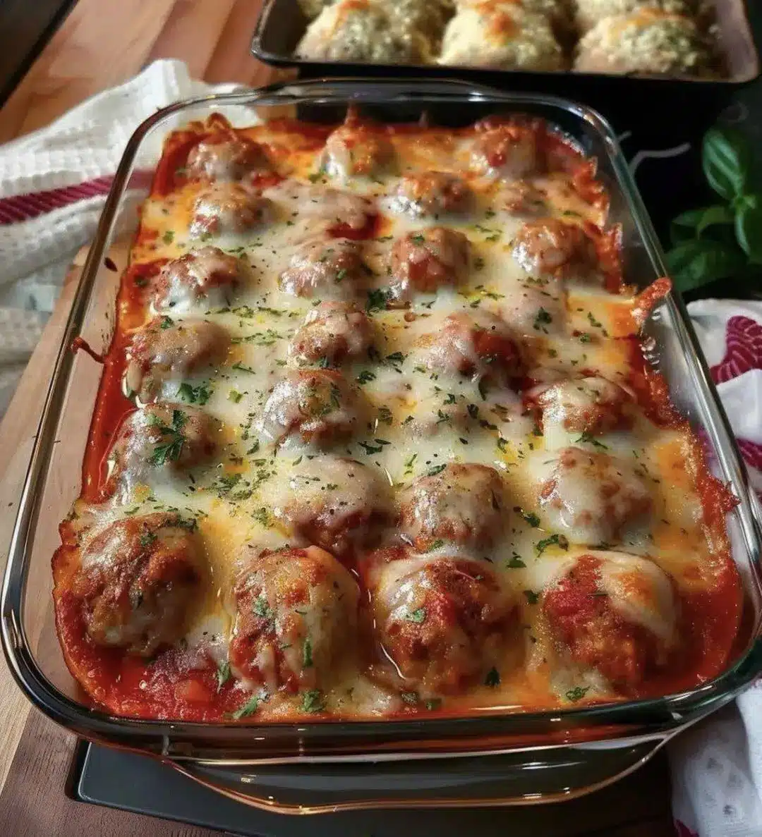 Close up of a cheesy meatball casserole with melted mozzarella and fresh parsley
