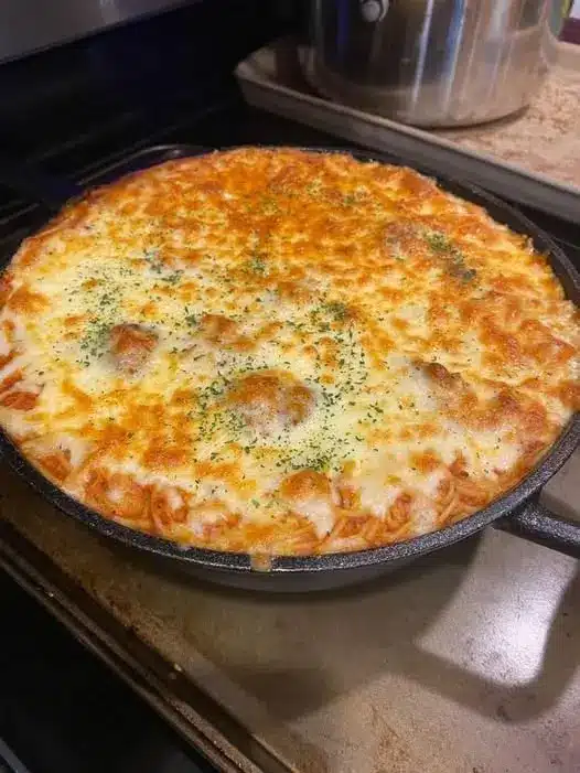 A scoop of melted cheese dip on a cracker being pulled away from a white baking dish