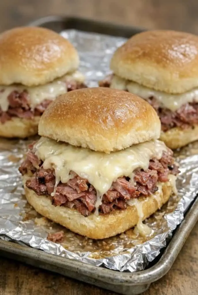 Close up view of a sliced corned beef slider showing the layers of meat, kraut, and melted cheese
