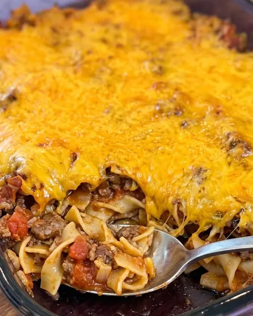 A serving of beef noodle casserole on a plate with a side salad