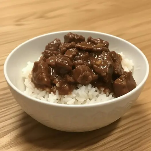 The finished dish of easy beef tips over rice served in a bowl with a side of vegetables