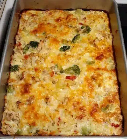 A slice of breakfast sausage casserole served on a plate with a side of fresh fruit.
