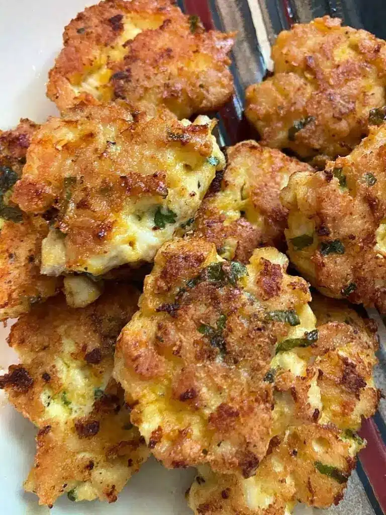 A stack of chicken fritters served with a side of creamy garlic dipping sauce