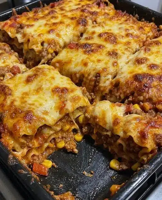 A serving of ground beef casserole on a white plate showing the layers of pasta and meat