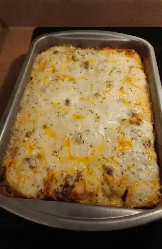 A serving of hash brown casserole on a plate showing the creamy potato interior and crispy topping.