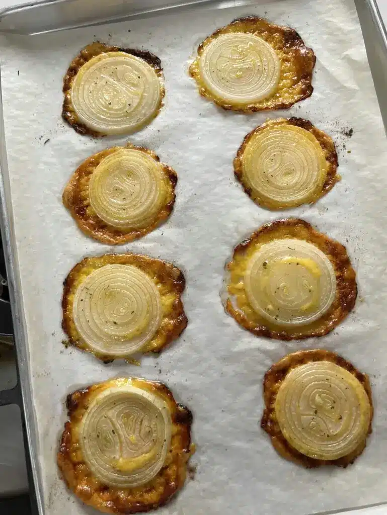 A plate of golden brown crispy cheesy onion rounds served with a side of ranch dipping sauce