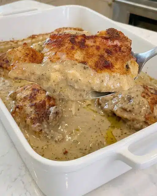 scooping a serving of easy chicken cordon bleu casserole showing melted swiss cheese and panko topping