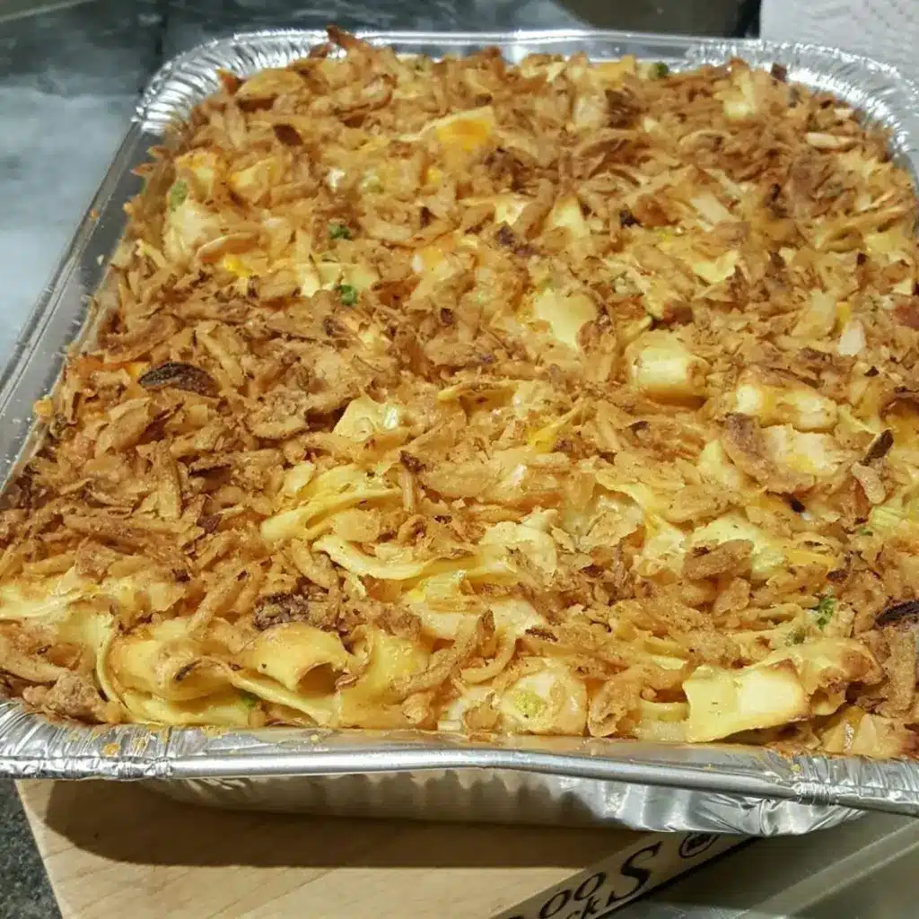 A serving of chicken crunch casserole on a white plate with a side of green beans