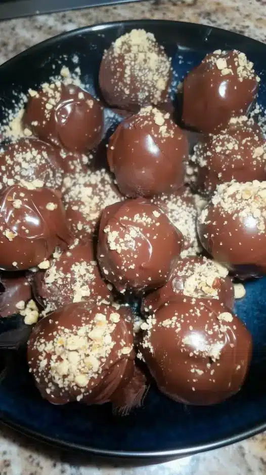 Platter of finished chocolate peanut butter truffles with a decorative chocolate drizzle