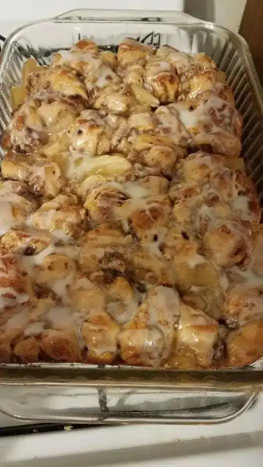 The finished cinnamon roll breakfast casserole drizzled with white icing and served on a plate.