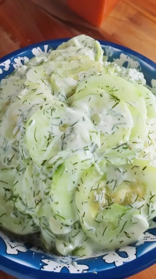 A bowl of creamy cucumber salad garnished with extra fresh dill