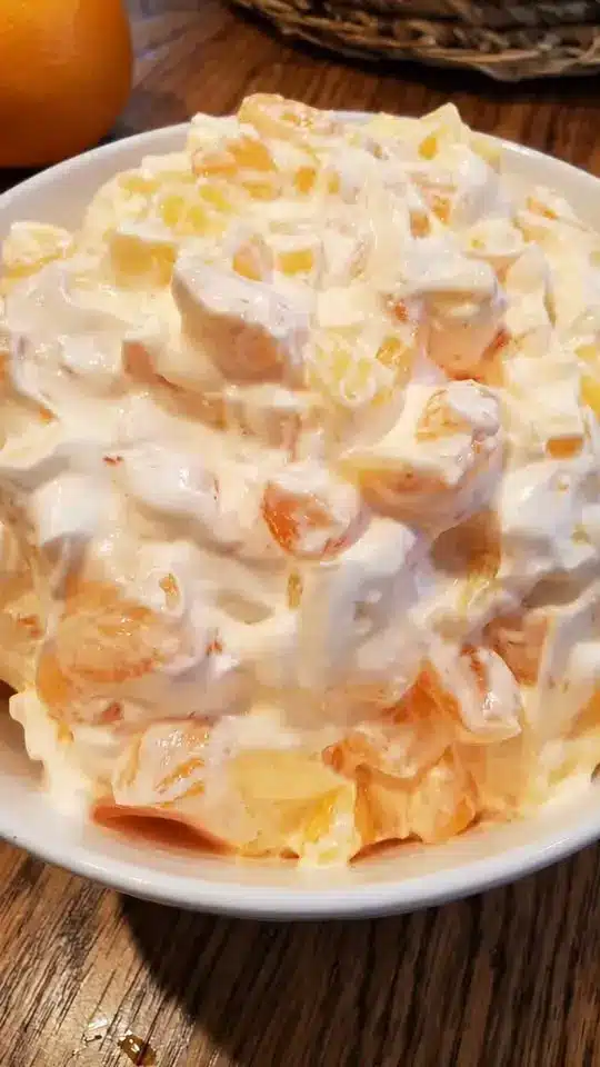 Completed creamy fruit salad garnished with mint in a serving bowl