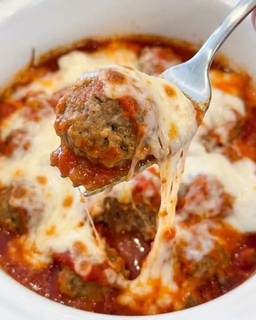 Cheesy meatballs served on a white plate with a side of toasted garlic bread and garnished with fresh parsley.