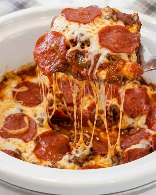 A serving of pizza casserole on a plate next to the slow cooker
