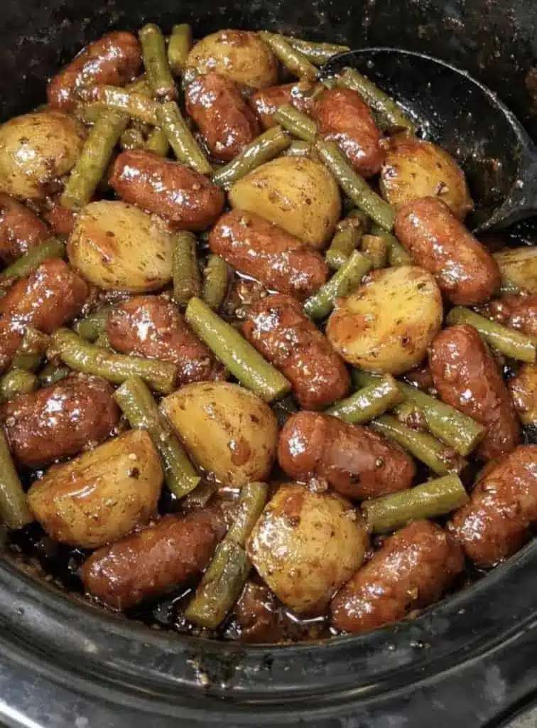 Finished crockpot sausage and potatoes served in a white bowl, garnished with fresh parsley.