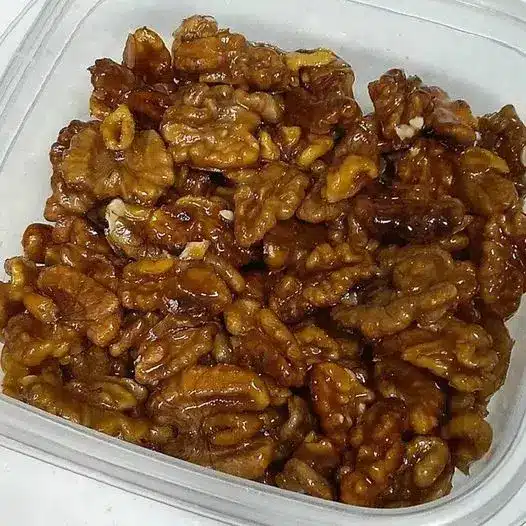 Finished caramel walnuts spread out on parchment paper to cool