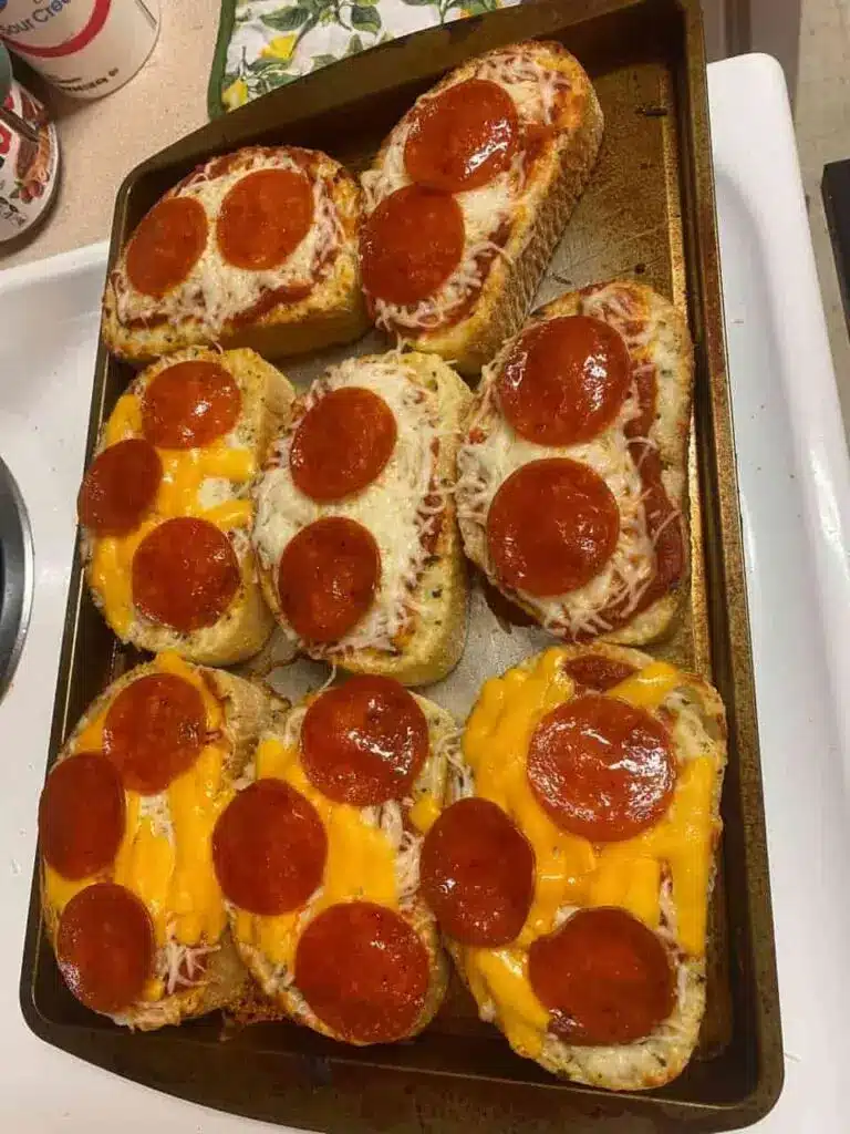 Several slices of garlic bread pizza arranged on a wooden board, showing the thick cheese and crispy edges.