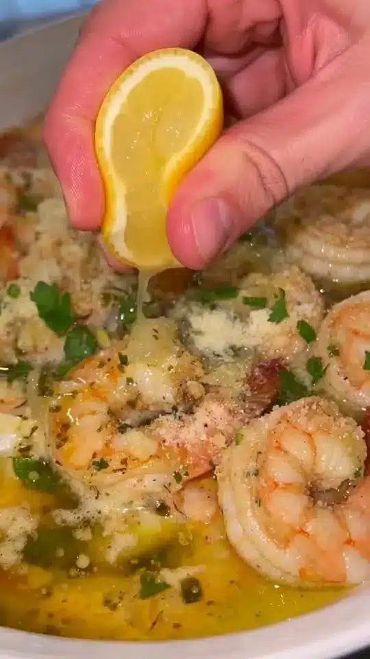 The finished garlic butter shrimp served in a bowl with a side of crusty bread and lemon wedges