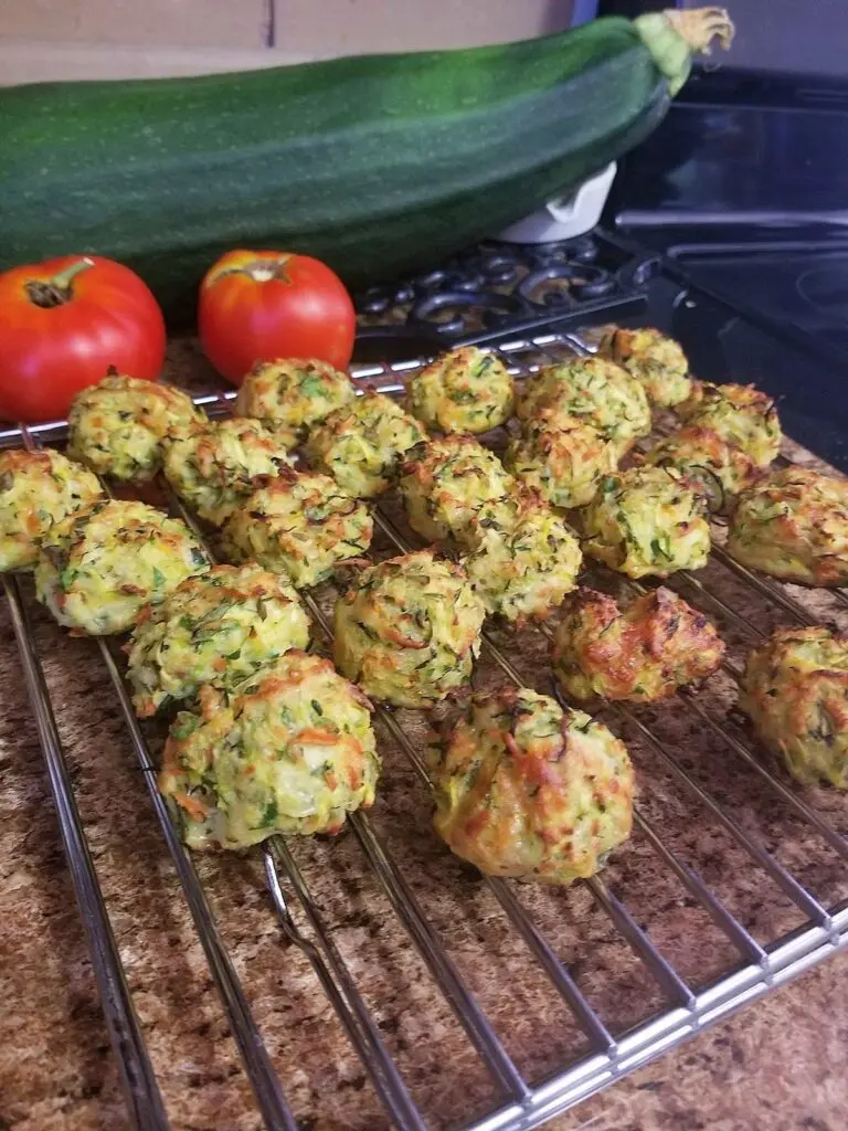 Golden brown roasted garlic zucchini bites in a serving bowl with a side of dipping sauce