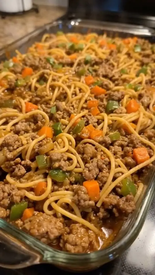 A serving of ground beef noodle casserole on a plate with a side of garlic bread