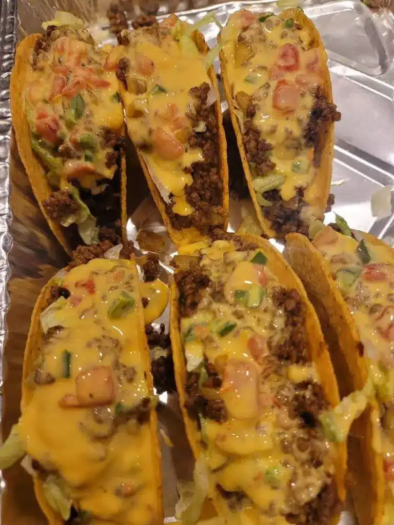 Assembled ground beef tacos with cheese, lettuce, and cilantro on a platter