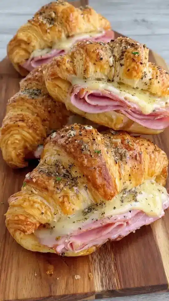 A plate of golden brown ham and cheese croissants served with fresh fruit