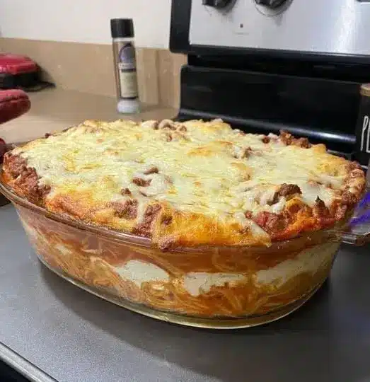 A golden, cheesy slice of baked spaghetti served on a white plate