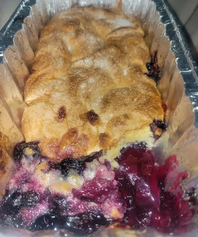 A finished blackberry cobbler served in a bowl with vanilla ice cream