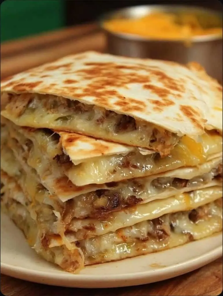 Sliced chicken quesadilla wedges served on a plate with dipping sauces.