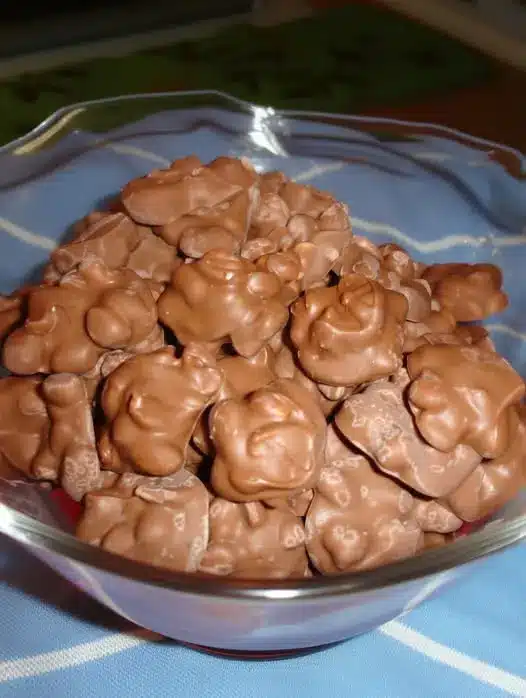 A finished plate of chocolate peanut clusters stacked on a white ceramic dish
