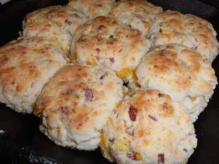 A close up of an omelet biscuit sandwich with melted cheese dripping down the side.
