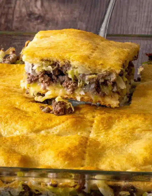 A sliced portion of runza casserole served on a white plate with a side salad.