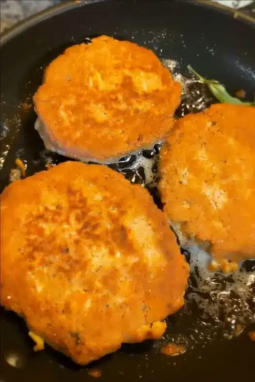 Golden brown crispy salmon patties served on a plate with lemon wedges and sauce