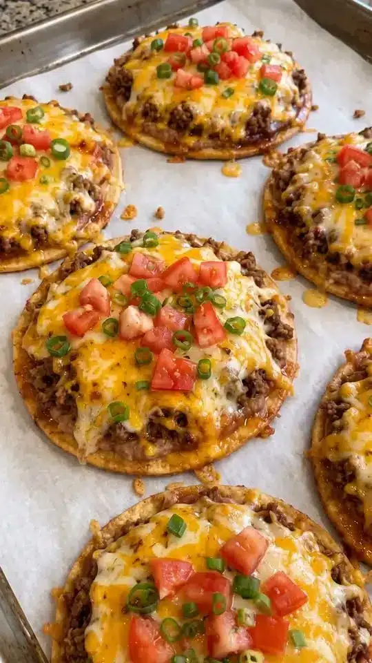 A close up view of several loaded potato bites garnished with sour cream and green onions.
