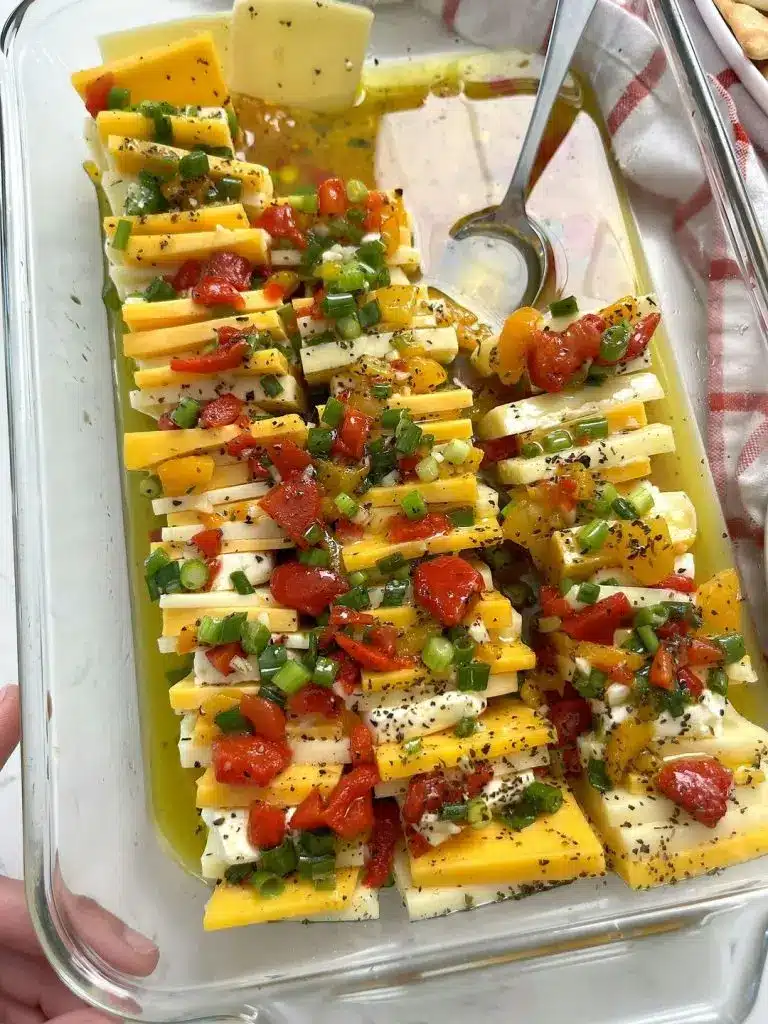 The finished marinated cheese served with crackers on a wooden board