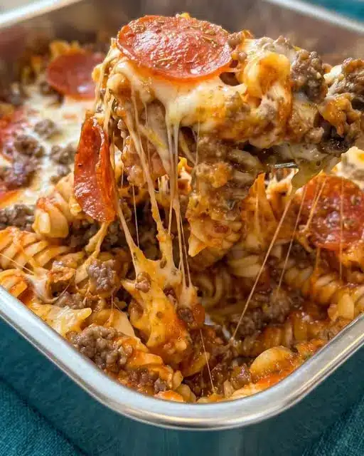 A slice of meat lovers casserole served on a plate, showing the layers of meat, melted cheese, and a golden crust.